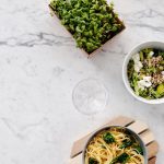 Flat lay of a nutritious meal with salad and pasta on a marble surface, perfect for healthy eating themes.